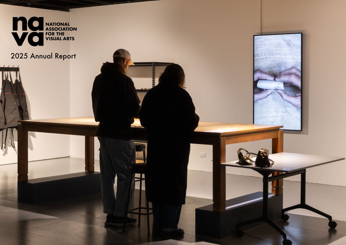 Photo of exhibition space with 2 people standing together at a large table with a screen on the wall in front of them displaying hands shaping a piece of clay. Sculptural objects on a smaller table to the right. Top left NAVA logo and “2025 Annual Report”