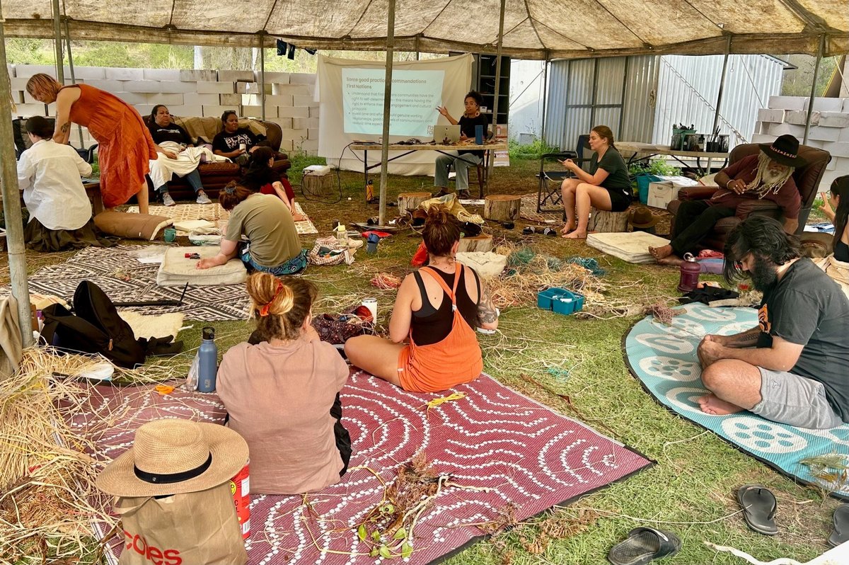 Photo of workshop in a large tent featuring weaving and a powerpoint presentation