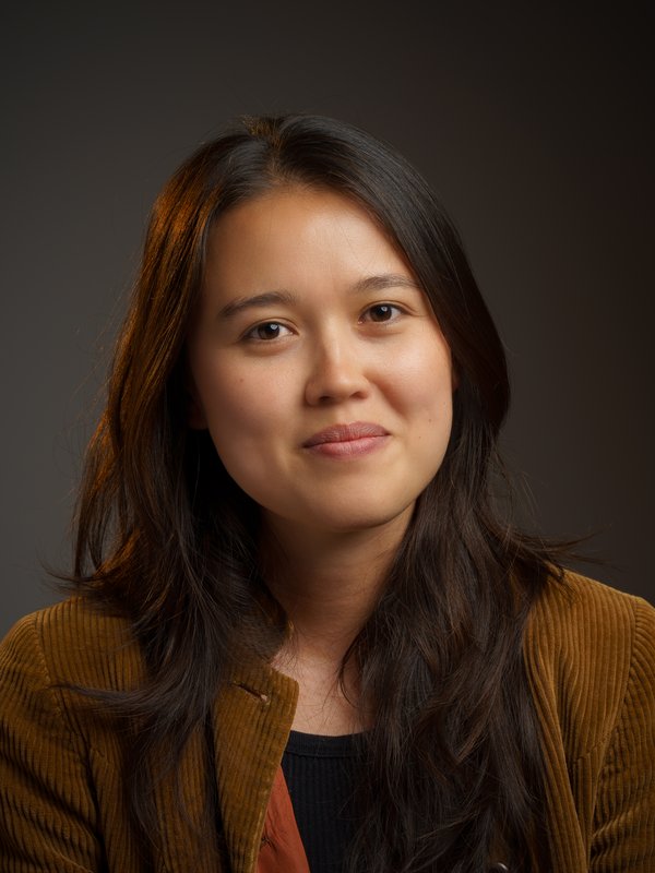 Protrait of Andrea wearing a brown jacket with a dark colour background