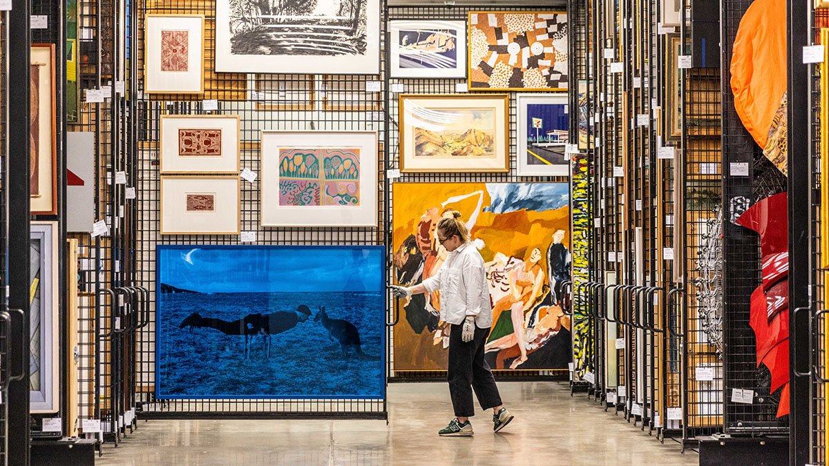 Photo of a person pulling out large artwork storage racks.