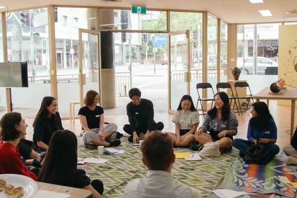 A group of young people sitting in a circle on the floor as part of a workshop at Pari, an artist-run initiative in Parramatta on Darug nation in NSW.