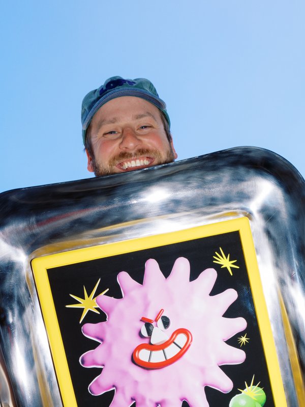 Artist Tim Meakins smiling behind his artwork.