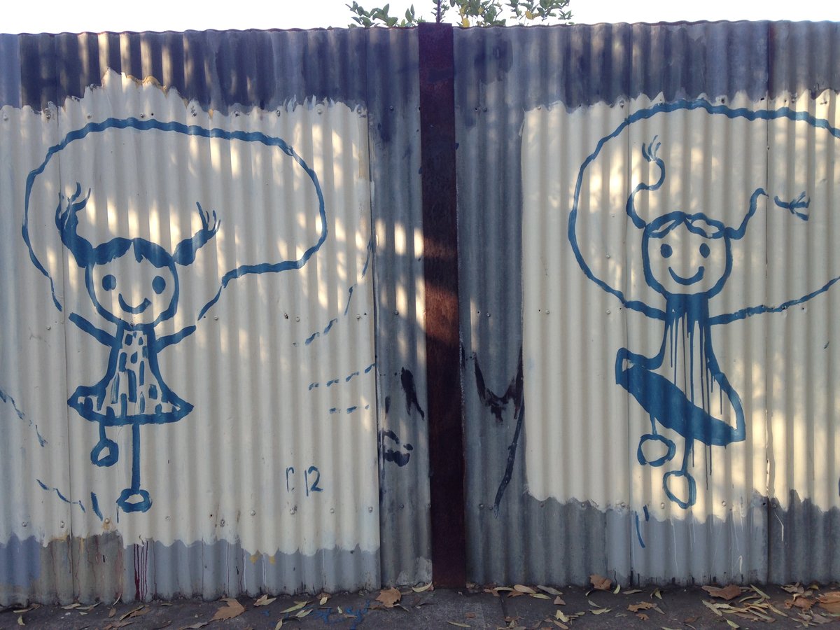 Images of two girls skipping painted on to a corrugated iron fence.