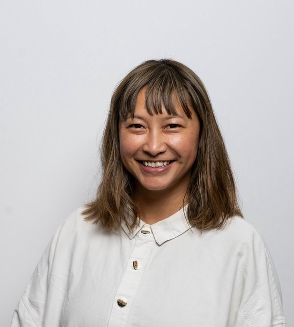 Photo of Jamie, against a white background, she is wearing a white shirt, has shoulder length hair and is smiling at the camera