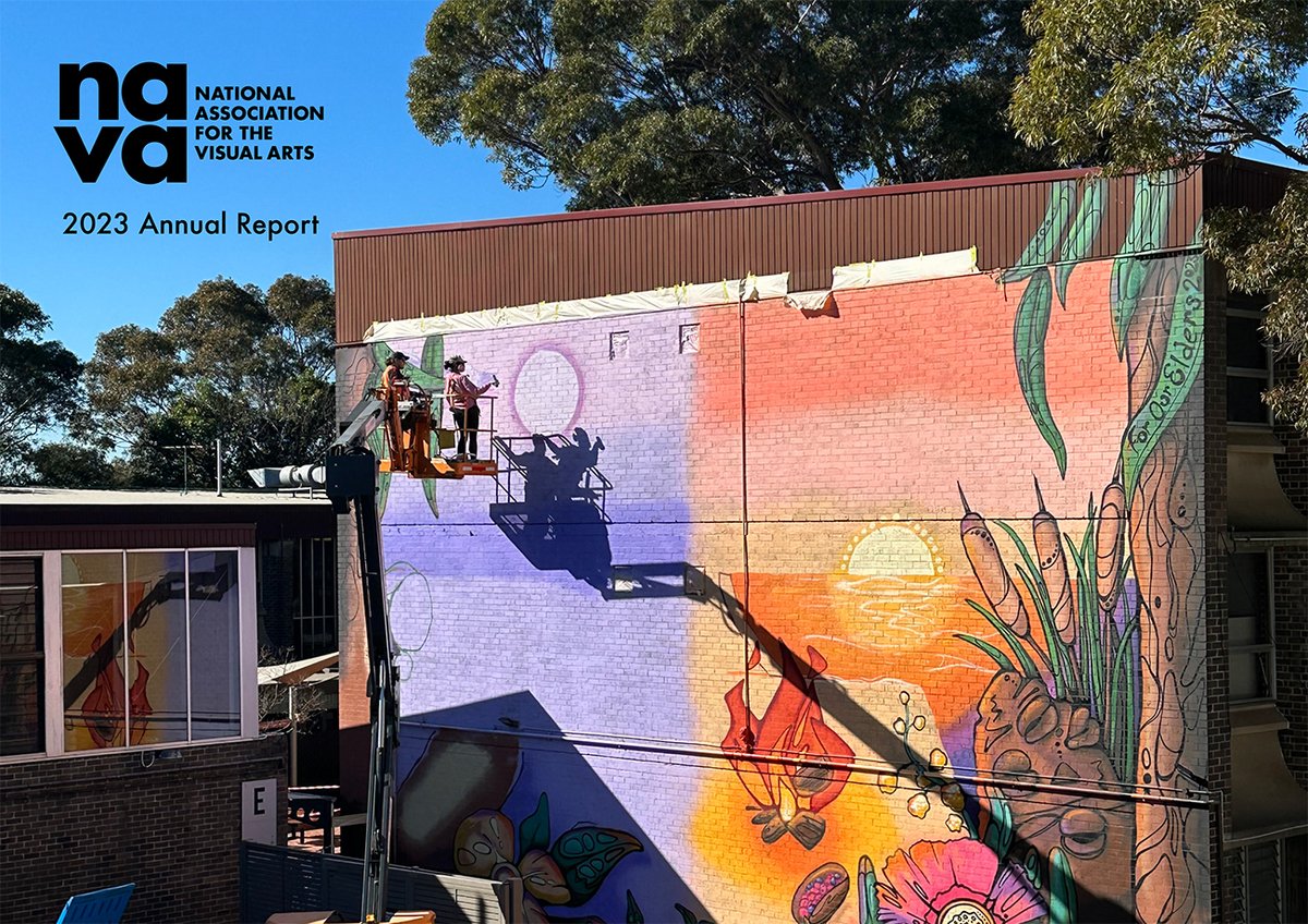 Photo of two people in a scissor lift at the top of a large wall featuring a brightly coloured mural, on one side is shades of purple, on the other, warm orange tones with a banksia, campfire, gum leaves and the words For Our Elders. 