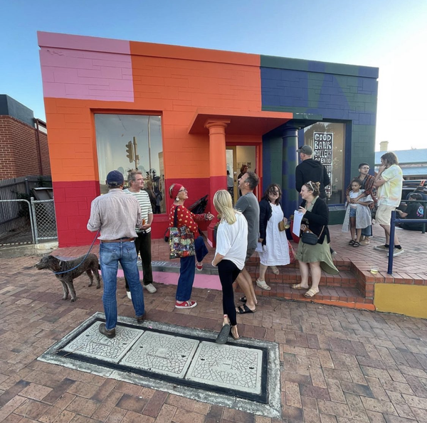 A group of people standing outside a brick building painted with bright blocks of colour